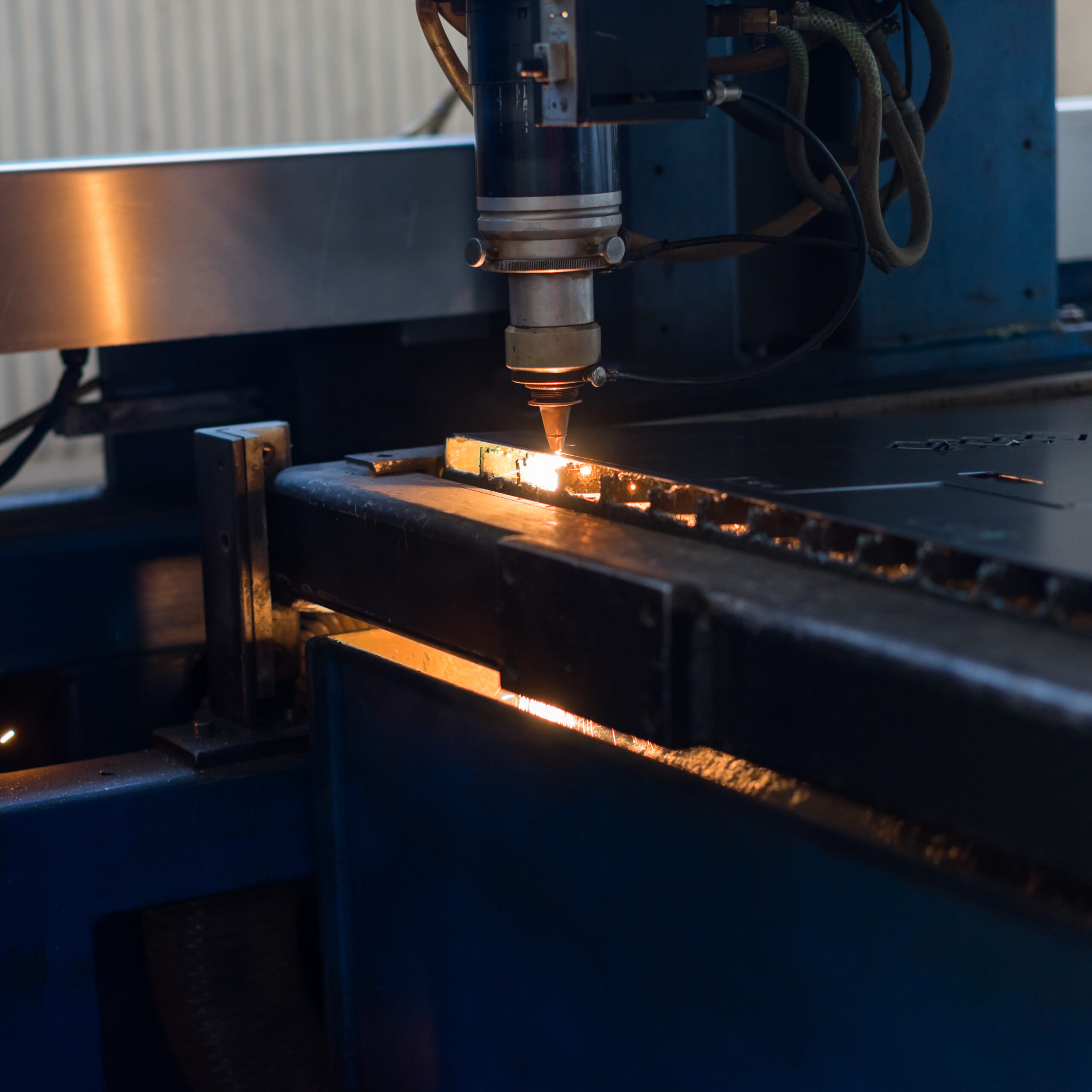 close-up of a laser head, cutting stencilled patterns into metal sheets